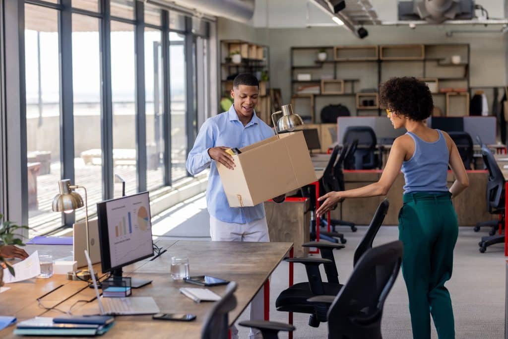 Man and a woman moving boxes and furniture in an office
