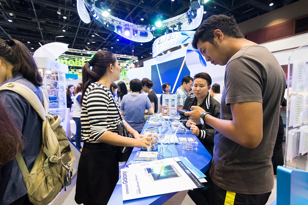 Multiple people standing around a table/booth at at trade show.